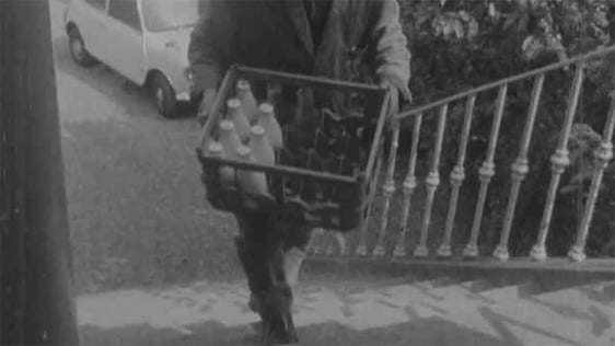 A milkman carries a crate of milk bottles in 1971.