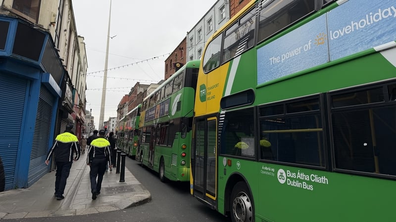 two gardai walk by a line of buses in dublin