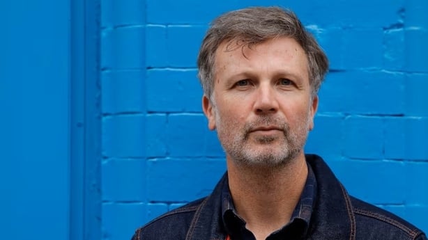 Paul Noonan headshot with blue background