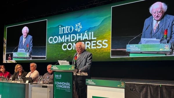 Michael D Higgins at a podium with screens behind him addressing the INTO conference