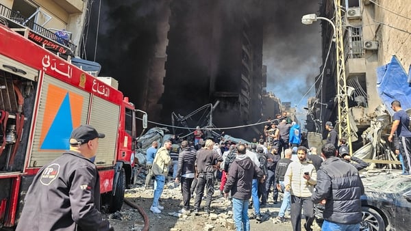First responders and residents stand amid rubble at the site of an Israeli airstrike