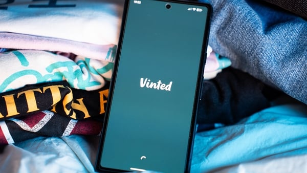 Vinted logo on a smartphone screen as the phone rests among clothing