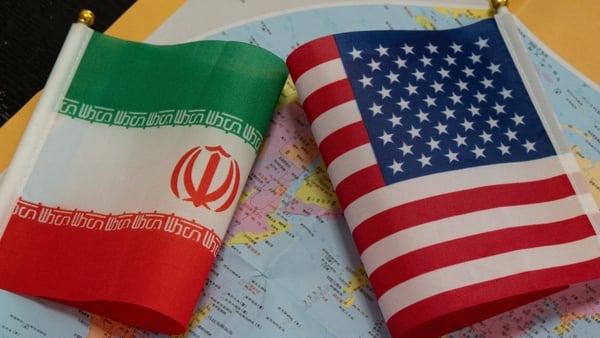 The national flags of the United States and Iran, with a world map in the background