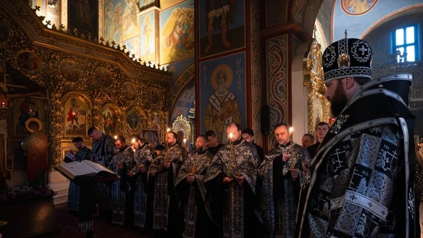 Worshippers attend Holy Thursday service inside St Michaels Cathedral in Kyiv Ukraine on April 9, 2026. Clergy dressed in black liturgical vestments stand in a line holding candles before a gilded iconostasis adorned with religious paintings and icons during the solemn Easter week ritual.