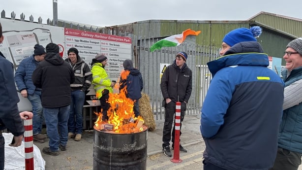 People attend a protest at Galway Port, surrounding a barrell with fire burning