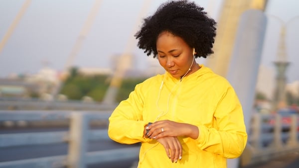 Young woman checking heart rate on smartwatch while running exercise, fitness tracking