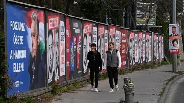 People walk in front of election poster billboards