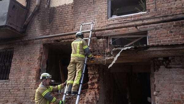 Firefighters work at the entrance to a residential building damaged by a drone strike in Sumy, Ukraine