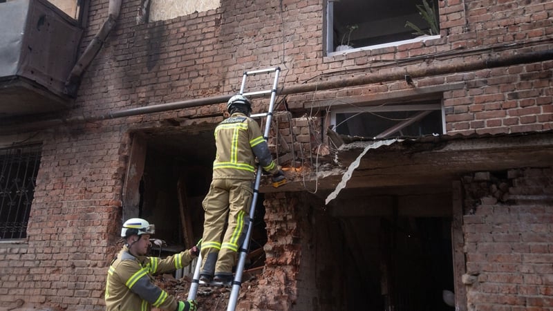 Firefighters work at the entrance to a residential building damaged by a drone strike in Sumy, Ukraine