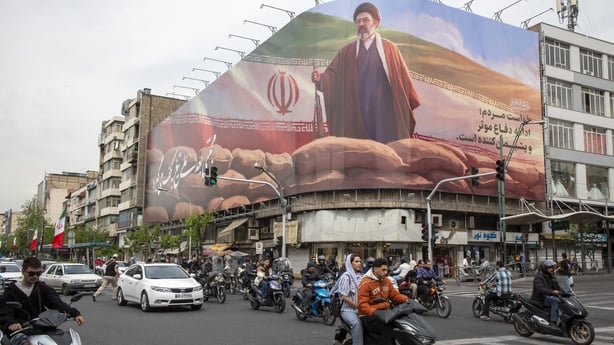 Motorists pass under a banner featuring a portrait of Mojtaba Khamenei, Iran's new Supreme Leader.
