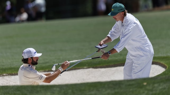 golfer Cameron Young exchanges clubs with his caddie Kyle Sterbinsky in a bunker