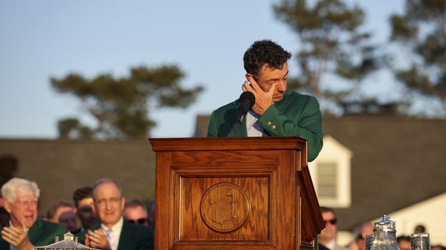 Rory McIlroy wipes his eyes as he speaks wearing a green jacket