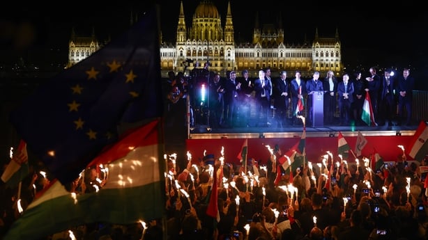 people hold candles and lights aloft at a gathering in Budapest
