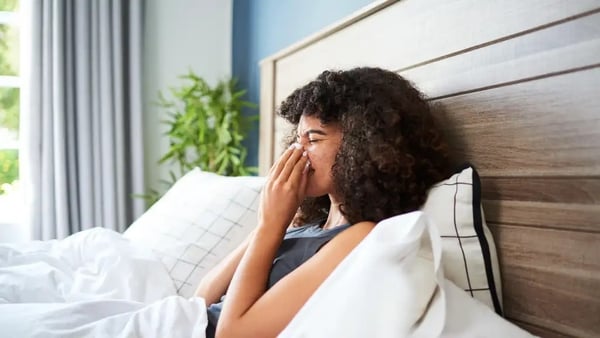 woman in bed sneezing