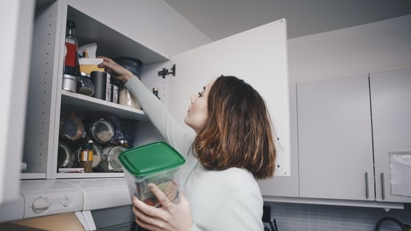 Young woman searching in cabinet at kitchen (Getty Images)