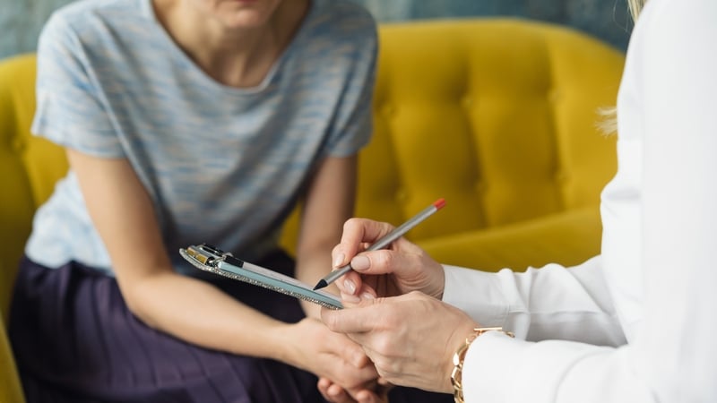 Woman writting to patient girl. Therapist's gestures. Female talks in coworking office. Mother and daughter talk about puberty problems. Top view (Getty Images)