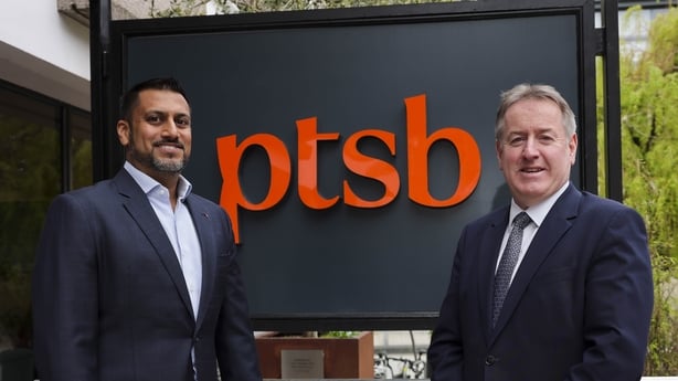 Sat Shah Deputy CEO of Bawag Group and Eamonn Crowley CEO of PTSB standing outside in front of PTSB branding