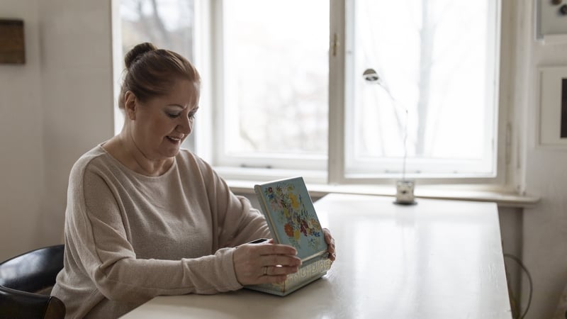 Image of senior woman looking in jewellery box at home