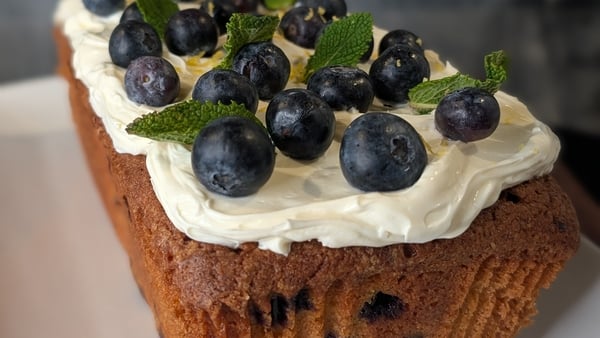 A loaf cake topped with blueberries and cream frosting
