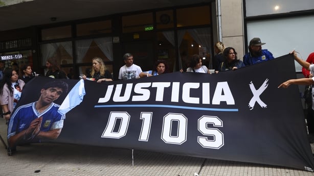 People hold a banner with the image of late Argentine soccer legend Diego Armando Maradona in Buenos Aires, Argentina, on April 14, 2026. A new trial against medical professionals facing accusations of negligence in connection to the 2020 death of the global icon is set to start. (Photo by Matias Ba