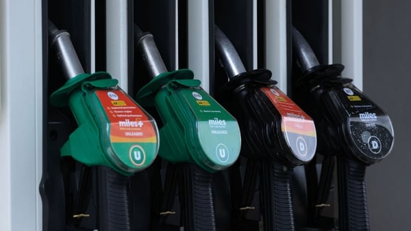 a row of four petrol and diesel pumps with green and black handles