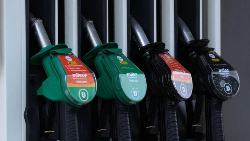 a row of four petrol and diesel pumps with green and black handles