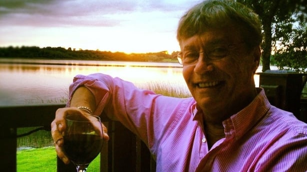 Eugene Maher smiling holding a glass of wine