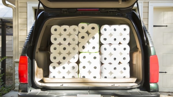 Image shows the trunk of a car stacked with mulitple packets of toilet paper.