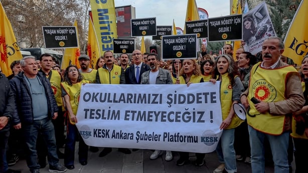 Image shows dozens of men and women dressed holding a banner in Turkish that says "we will not surrender our schools to violence".