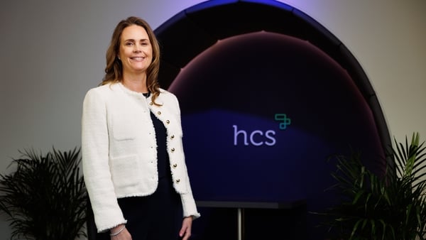 Image of a businesswoman in a white jacket standing beside HCS branding
