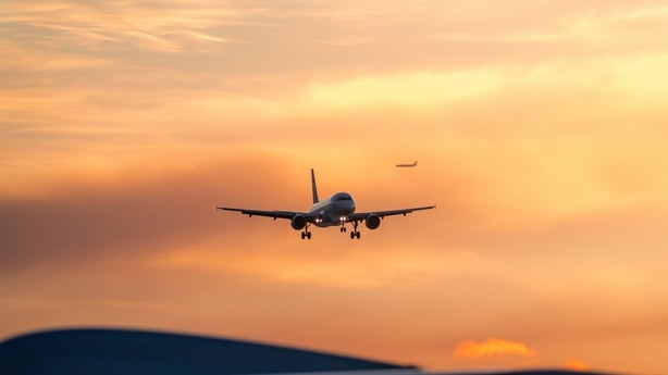 An airport during sunset, with planes arriving and departing against a colorful sky