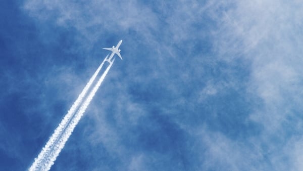 Airplane flying with high speed on blue sky background seen from the ground