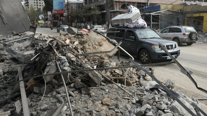 Displaced residents drive past a destroyed building as they return back to the southern Lebanese city of Nabatieh