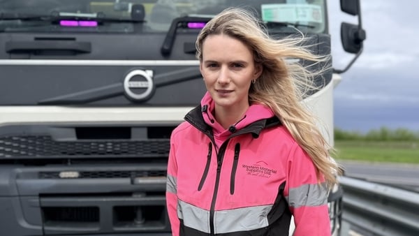 Sarah Wiers wears a pink work hi-vis work jacket and stands in front of a truck