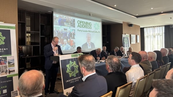 Michael Collins speaks to an assembled audience with a power point presentation on a big screen
