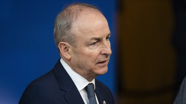 a photograph of micheal martin speaking to reporters