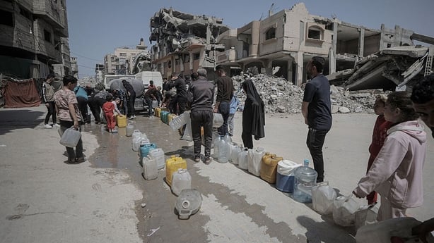 Palestinians in the Sheikh Radwan neighborhood collect water from tanker trucks and carry it in containers to their homes