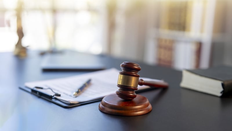 Gavel resting on a dark desk with legal documents, pen, and law book illustrating justice