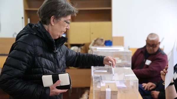 a woman casts her vote into a plastic ballot box