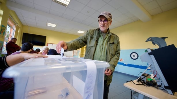 a man casts his vote into a plastic ballot box