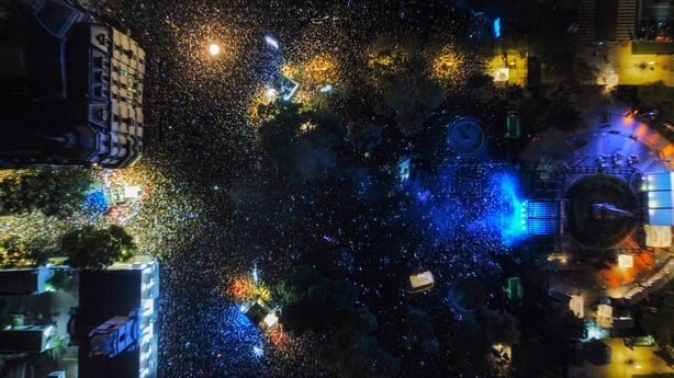 aerial view of massive crowds of people in a giant square at night