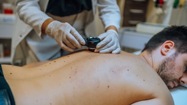 Dermatologist examining patient skin moles with dermoscope at clinic