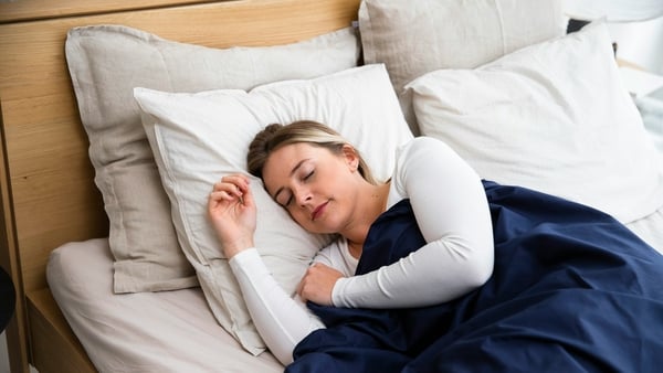 Woman sleeping in bed, covered by blue sheet (Photo by Slaapwijsheid.nl on Unsplash)