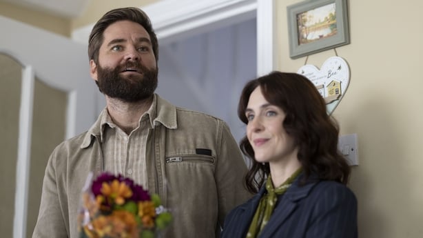 Daryl (Rick Donald), holding flowers, stands beside Shiv (Róisín Gallagher) in The Dry