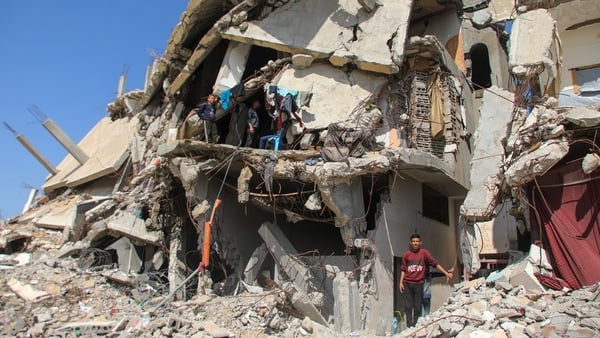People walk past destroyed homes in Gaza City, Gaza