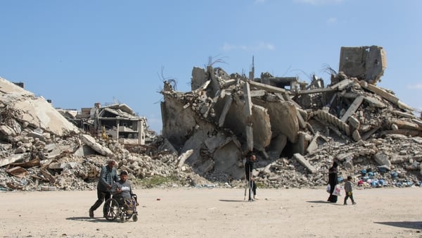 People walk past homes destroyed by Israeli airstrikes in Gaza City, Gaza