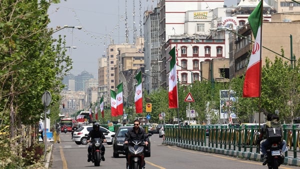 Vehicles and motorbikes drives along a street adorned with the Iranian flag, in Tehran, Iran