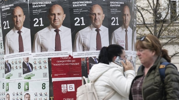 Pedestrians walk past election posters of the Progressive Bulgaria coalition's leader and former President Rumen Radev in Sofia 