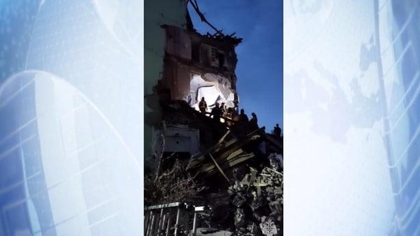 rescue workers stand on top of the rubble of a damaged apartment building in Russia