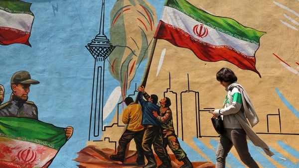 An Iranian woman walks past an anti-USA and anti-Israel mural